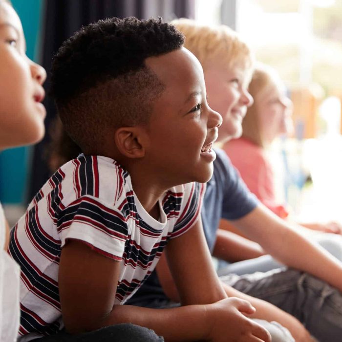 group-of-elementary-school-pupils-sitting-on-floor-listening-to-teacher.jpg